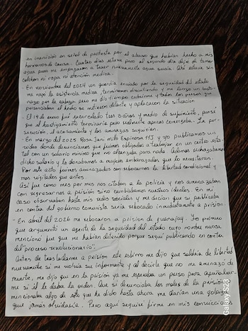 Hoja de papel blanco con texto manuscrito en tinta negra, ubicada sobre una superficie de madera oscura