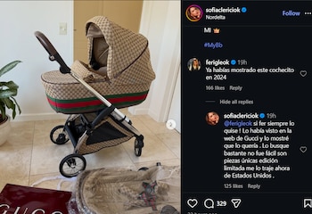 Cochecito de bebé de lujo con patrón monograma de Gucci y franja verde-roja sobre un suelo de baldosas, con una planta y una bolsa roja de la marca