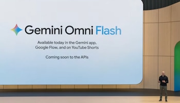 Demis Hassabis de pie en un escenario, mirando hacia la audiencia, con una gran pantalla brillante detrás que muestra el nombre del producto Gemini Omni Flash