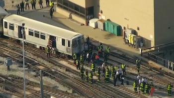 Vista aérea de un tren plateado detenido en las vías del ferrocarril. Se ven socorristas y civiles alrededor, con una escalera en la puerta de un vagón