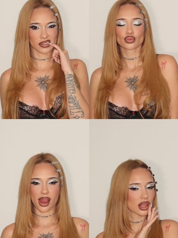 La Joaqui de cerca con cabello rubio liso, maquillaje de ojos plateado brillante, labios marrones y lengua asomando. Lleva un top de encaje negro y muestra tatuajes