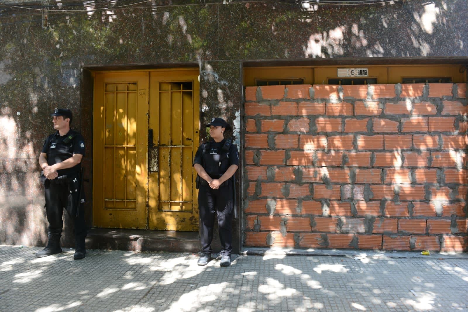 Dos agentes de policía custodian la entrada tapiada de ladridos de uno de los inmuebles que habían sido usurpados