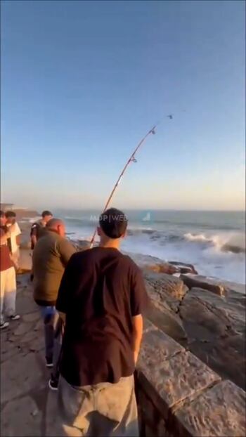 Jóvenes celebrando junto al pescador tras sacar el pez en Mar del Plata