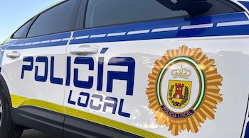 Lateral de un vehículo blanco con franjas azules y amarillas. Se lee 'Policía Local' en azul y el escudo de la Policía Local de Los Barrios