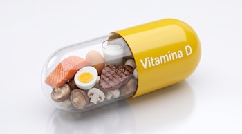 Cápsula con texto Vitamina D en una mitad amarilla y salmón, huevo, un vaso de leche, carne y hongos en su mitad transparente sobre fondo blanco.