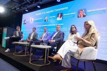 Seis personas sentadas en butacas sobre un escenario frente a una gran pantalla azul con texto, fotos y el logotipo Cámara de Medios de Pago