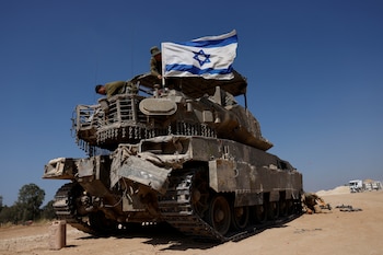 Soldados israelíes montan una bandera israelí en un vehículo militar cerca de la frontera entre Israel y Gaza (REUTERS/Amir Cohen)