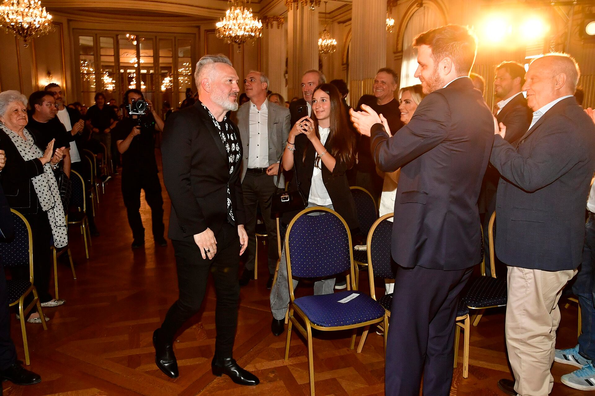 Kolankowsky rumbo a recibir el diploma con los aplausos de Ferrario y Lombardi. Atenta, lo mira su hija Ámbar