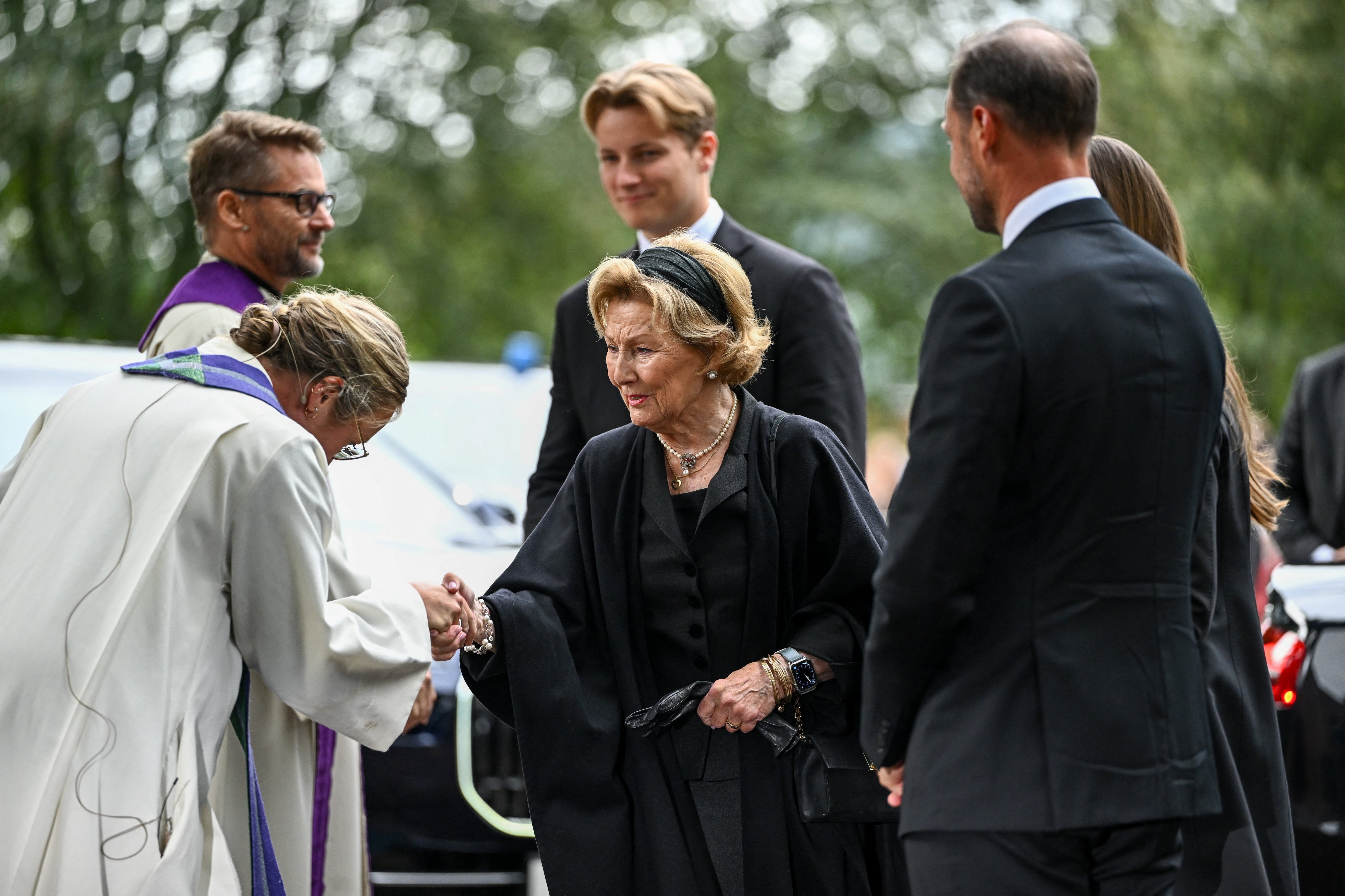 La reina Sonja de Noruega, el rey Haakon, la princesa heredera Ingrid Alexandra (parcialmente visible) y el príncipe Sverre Magnus a su llegada a la iglesia de Asker para asistir a un servicio conmemorativo en honor al difunto rey Harald, el 30 de agosto de 2026. (REUTERS/Dylan Martinez)