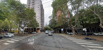 Cruce vial urbano con pavimento señalizado como avenida 53, árboles, edificios de departamentos y vehículos en circulación