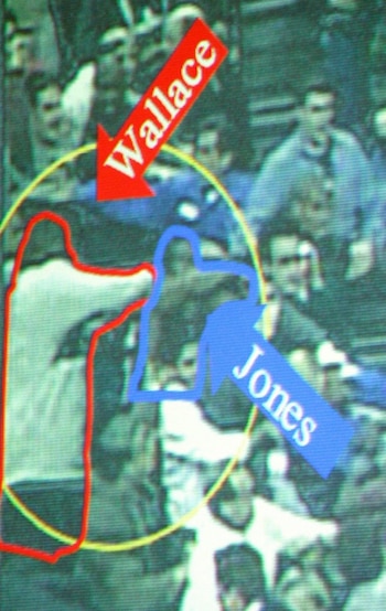Fotografía borrosa de una multitud con dos figuras resaltadas por contornos rojo y azul. Flechas rojas y azules los identifican como Wallace y Jones