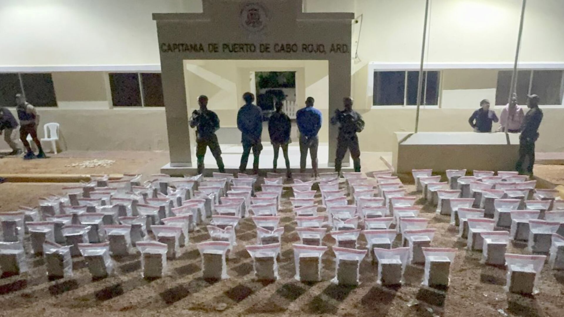 Fotografía cedida por la Dirección Nacional de Control de Drogas de la República Dominicana (DNCD) que muestra tres detenidos junto a paquetes de cocaína incautados durante una intervención en apoyo a la Operación Lanza del Sur de los Estados Unidos este lunes, en Santo Domingo (EFE/Dirección Nacional de Control de Drogas de la República Dominicana)