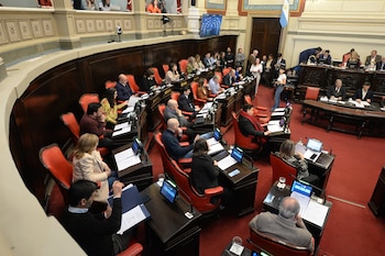 Senadores sentados en sus bancas de madera con asientos rojos durante una reunión en un recinto legislativo