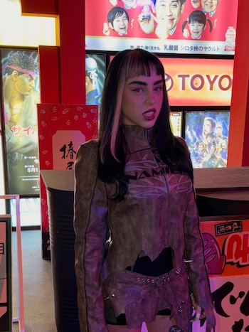 Nicki Nicole muestra su nuevo corte de cabello con flequillo recto y melena oscura mientras posa con los ojos entrecerrados y los labios pintados de rojo.