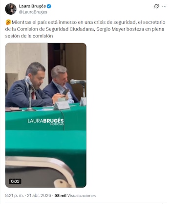 Sergio Mayer, un hombre de cabello canoso, bosteza ampliamente sentado en una mesa con un micrófono, junto a otro hombre que mira su teléfono