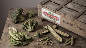 Brócoli, lechuga, calabacín, guisantes, y caja de madera con logo Prince de Bretagne y texto Bretaña, Francia.