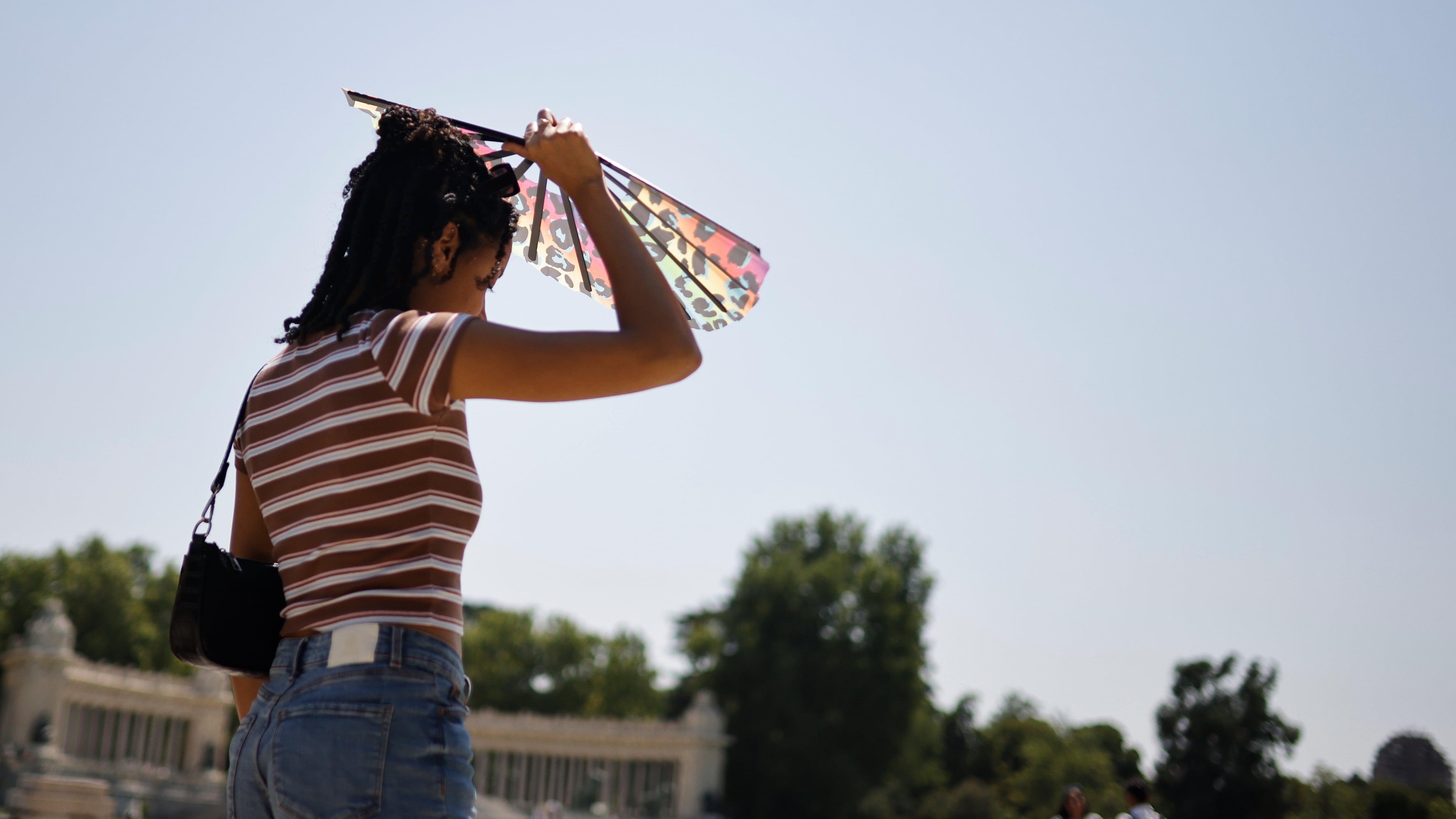 Una chica se protege del sol con un abanico en el parque de El Retiro de Madrid. (EFE/ Marcos Villaoslada)