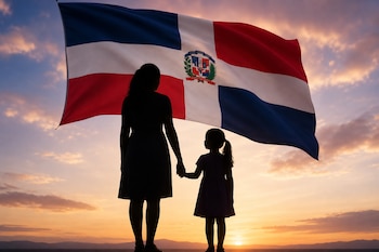 Siluetas a contraluz de una mujer y una niña tomadas de la mano con la bandera de República Dominicana sobre un cielo al atardecer.