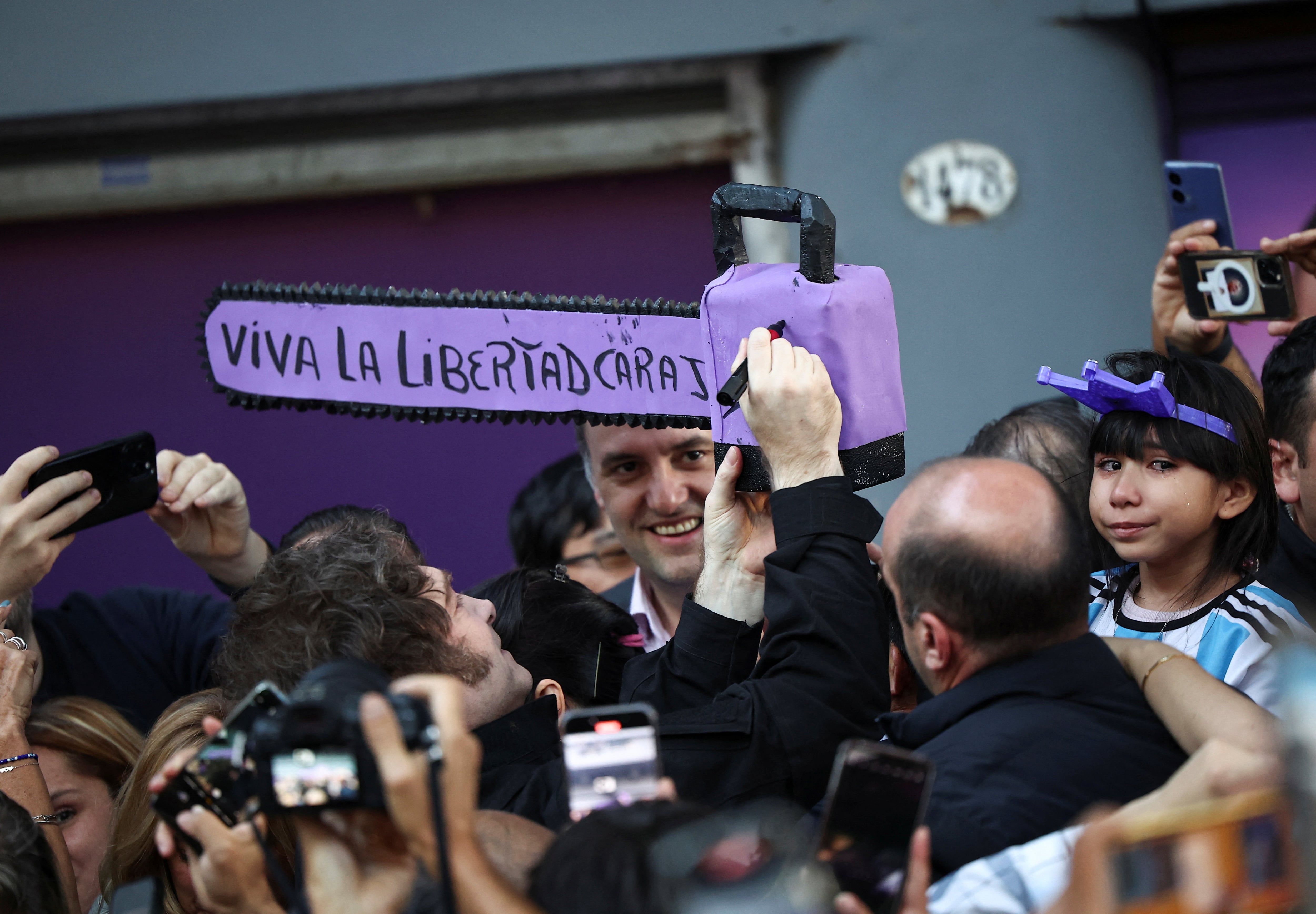 Javier Milei y Manuel Adorni junto a una motosierra que simboliza el recorte del gasto público (REUTERS)