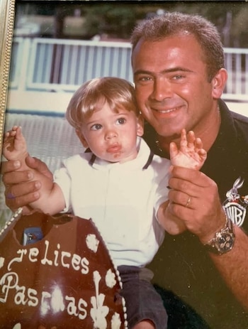 Marcelo Pelegri sonríe mientras sostiene a un niño pequeño con la cara manchada, junto a una torta de "Felices Pascuas"