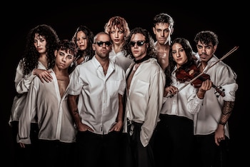 Diez personas, seis hombres y cuatro mujeres, visten camisas blancas y pantalones negros. Dos hombres usan gafas de sol. Una mujer sostiene un violín. Fondo negro