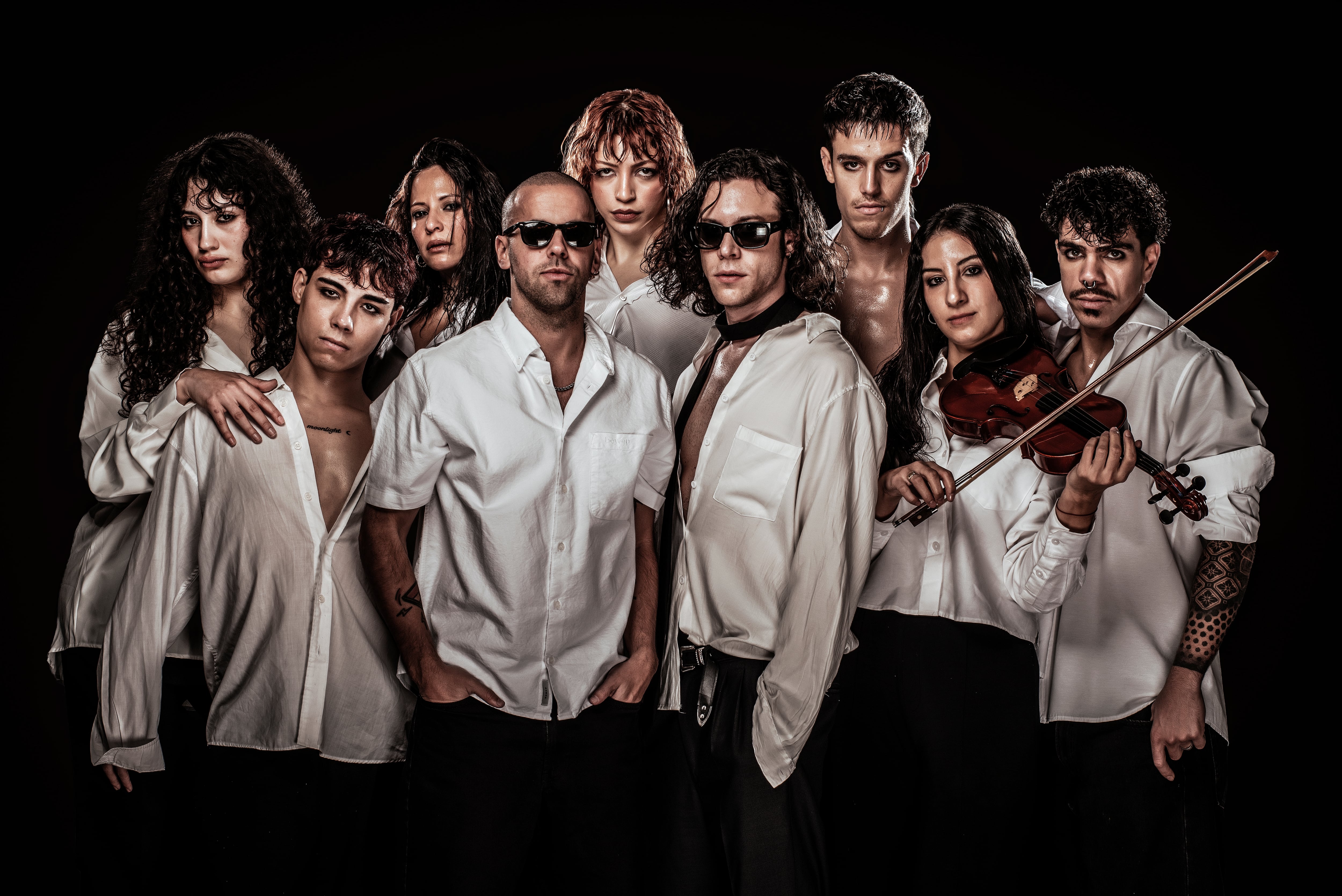 Mati Napp y Alan Madanes posan junto al elenco de Animal, ataviados con camisas blancas y pantalones oscuros sobre un fondo negro.