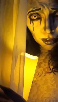 Una caracterización artística combina maquillaje facial blanco y detalles oscuros bajo una luz de tono amarillo. (Aztlán. Feria de Chapultepec/ Instagram)