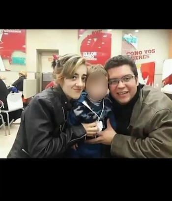 Una mujer, un hombre con gafas y un niño con cara borrosa sonríen a la cámara dentro de un restaurante de comida rápida con decoración roja