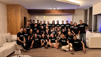 Cuarenta personas, con camisetas negras con el logo "Integrando Salud", posan en grupo en un interior con sofás y pared de madera