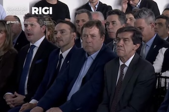 Varios hombres vestidos de traje formal sentados en un auditorio frente a un gráfico que indica Ronda de Negocios RIGI