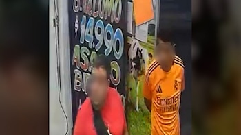 Dos personas con rostros borrosos, una de rojo y otra de naranja, frente a un banner publicitario oscuro con precios grandes y la imagen de una vaca