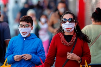 Personas con tapabocas caminan frente