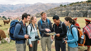 Cinco personas con mochilas y cámaras miran un mapa. Al fondo hay un muro de piedra, montañas, una ciudad, tres llamas y dos mujeres con atuendos tradicionales.