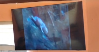 Televisor colocado sobre una pared que exhibe una imagen difusa con una figura clara sobre un fondo oscuro