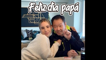Mujer joven con cabello largo y suéter claro junto a hombre asiático sonriente, señalando hacia arriba, con el texto "Feliz día papá" sobre la imagen