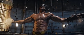 Wolverine sin camiseta con máscara negra y pantalones amarillos extiende los brazos, rodeado de chispas en una estructura metálica oscura
