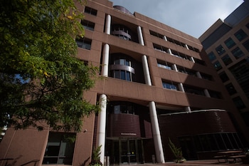 Fachada de un edificio marrón de varios niveles con columnas blancas cilíndricas y una entrada acristalada con la inscripción Whitehead Institute