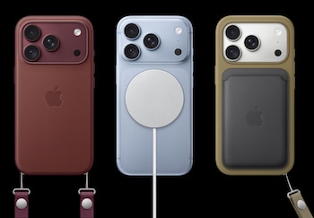Tres teléfonos inteligentes dispuestos en fila con fundas de color rojo y beige, un cargador magnético circular y un tarjetero sobre fondo negro