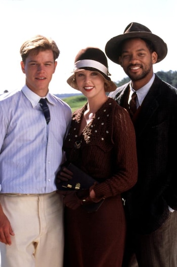 Matt Damon, Charlize Theron y Will Smith sonríen a cámara. Llevan vestuario de época: Damon, camisa y corbata; Theron, vestido y sombrero; Smith, traje y sombrero