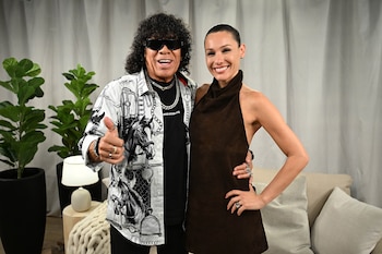 Pampita y La Mona posan sonrientes. Él lleva gafas de sol, camisa estampada y pulgar arriba. Ella, un top marrón halter, con el pelo recogido