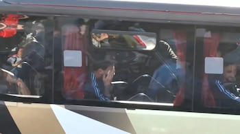 Lionel Messi sentado junto a la ventanilla dentro de un autobús con cortinas rojas y cristales oscuros.