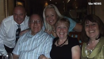 Cinco adultos sonrientes (tres mujeres y dos hombres) posan en un interior con poca luz, uno de los hombres usa gafas y una mujer lleva un collar