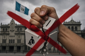 Una mano aplasta y rompe una urna de piedra con el símbolo de votación, cruzada por dos líneas rojas, con una bandera guatemalteca al fondo.