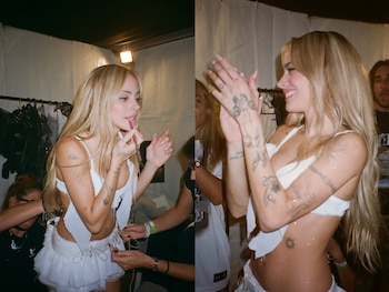 Tini Stoessel, rubia de cabello largo, se maquilla y se viste con un atuendo blanco brillante en el backstage. Sonríe y aplaude, mostrando brillo en su piel y tatuajes