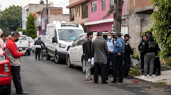 Varios agentes policiales, civiles y vehículos con el rótulo Investigación Criminal permanecen estacionados en una calle con edificios.