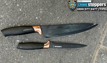 Dos cuchillos de hoja negra sobre pavimento de concreto junto al logotipo de Crime Stoppers de la Policía de Nueva York
