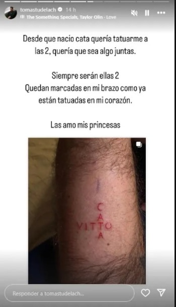Primer plano del antebrazo peludo de un hombre con un tatuaje fresco y rojizo. Se leen los nombres "CATA" en vertical y "VITTO" en horizontal, formando una cruz