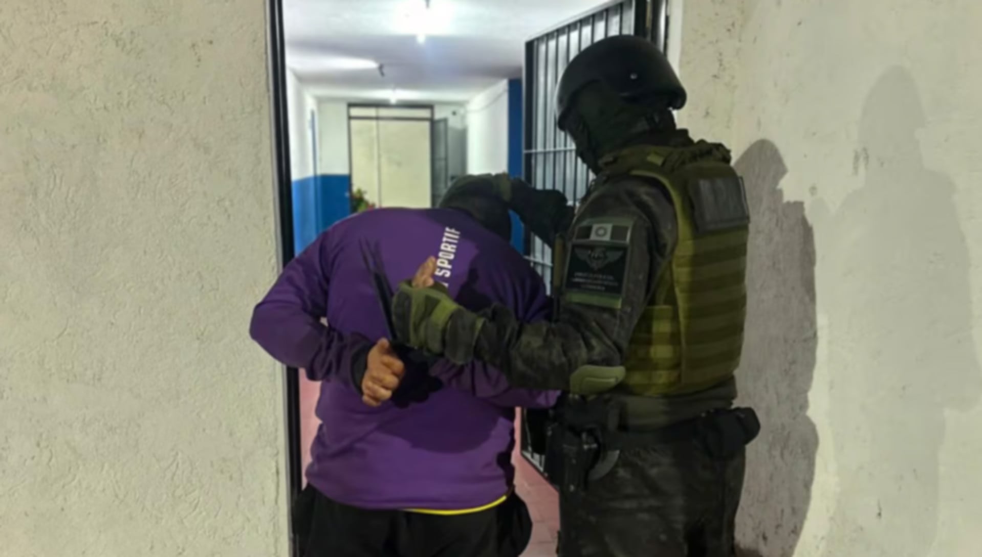 Un agente de seguridad detiene a un hombre, presunto integrante de una banda narco que operaba desde un galpón usurpado del ferrocarril en Cruz del Eje, Córdoba(El Doce.tv)