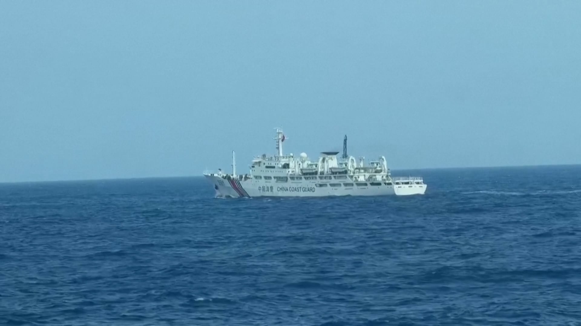 Una embarcación grande y blanca de la Guardia Costera de China navega en aguas azules bajo un cielo despejado
