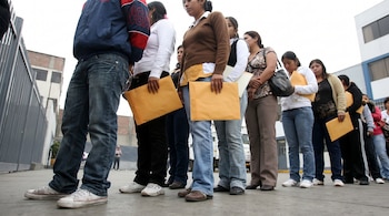 Una fila de personas, incluyendo un hombre y varias mujeres, sostienen sobres de manila amarillos. Se aprecian sus cuerpos y edificios al fondo.
